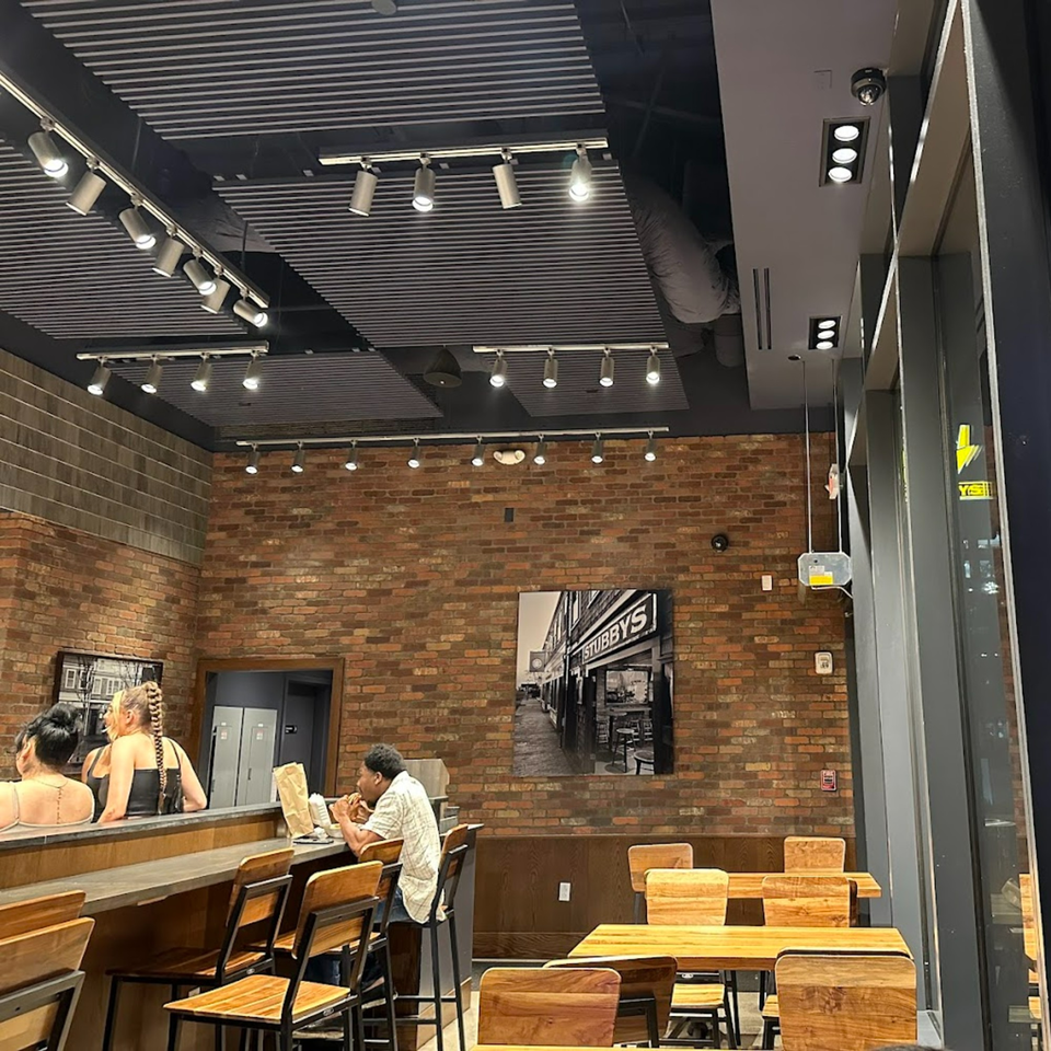 Interior of Stubbys restaurant with brick walls, track lighting, and customers dining at a bar and tables.