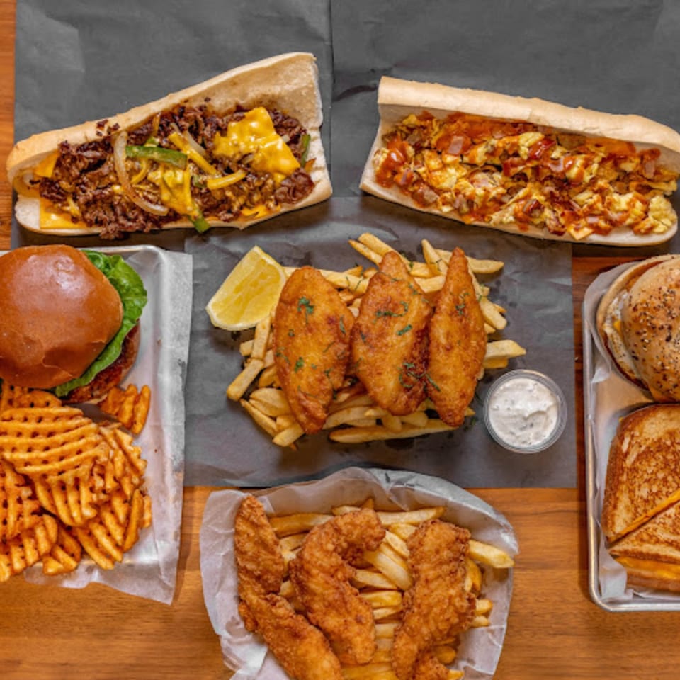 An overhead shot of various American dishes from Stubbys, including subs, burgers, fish, and chicken tenders with fries.