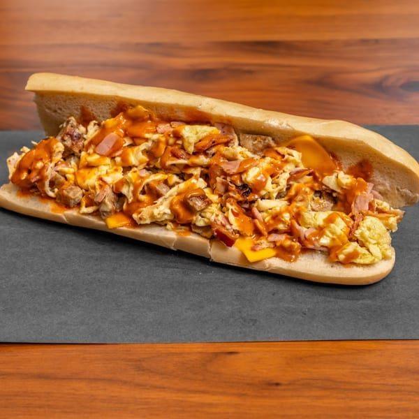 A Stubbys American breakfast sub sandwich, filled with scrambled eggs, cheese, and meat, drizzled with sauce.