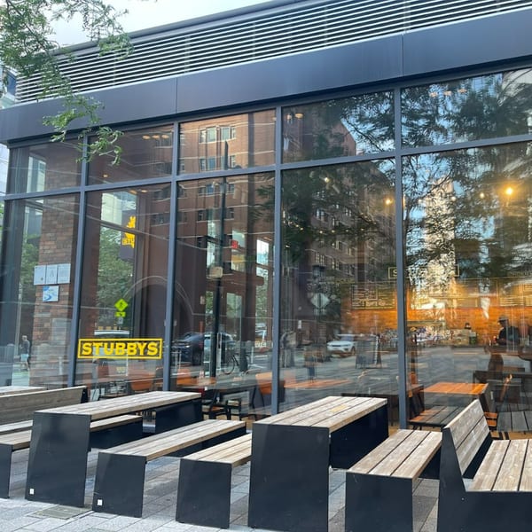 Exterior of Stubbys restaurant with large glass windows reflecting the street and outdoor picnic tables.